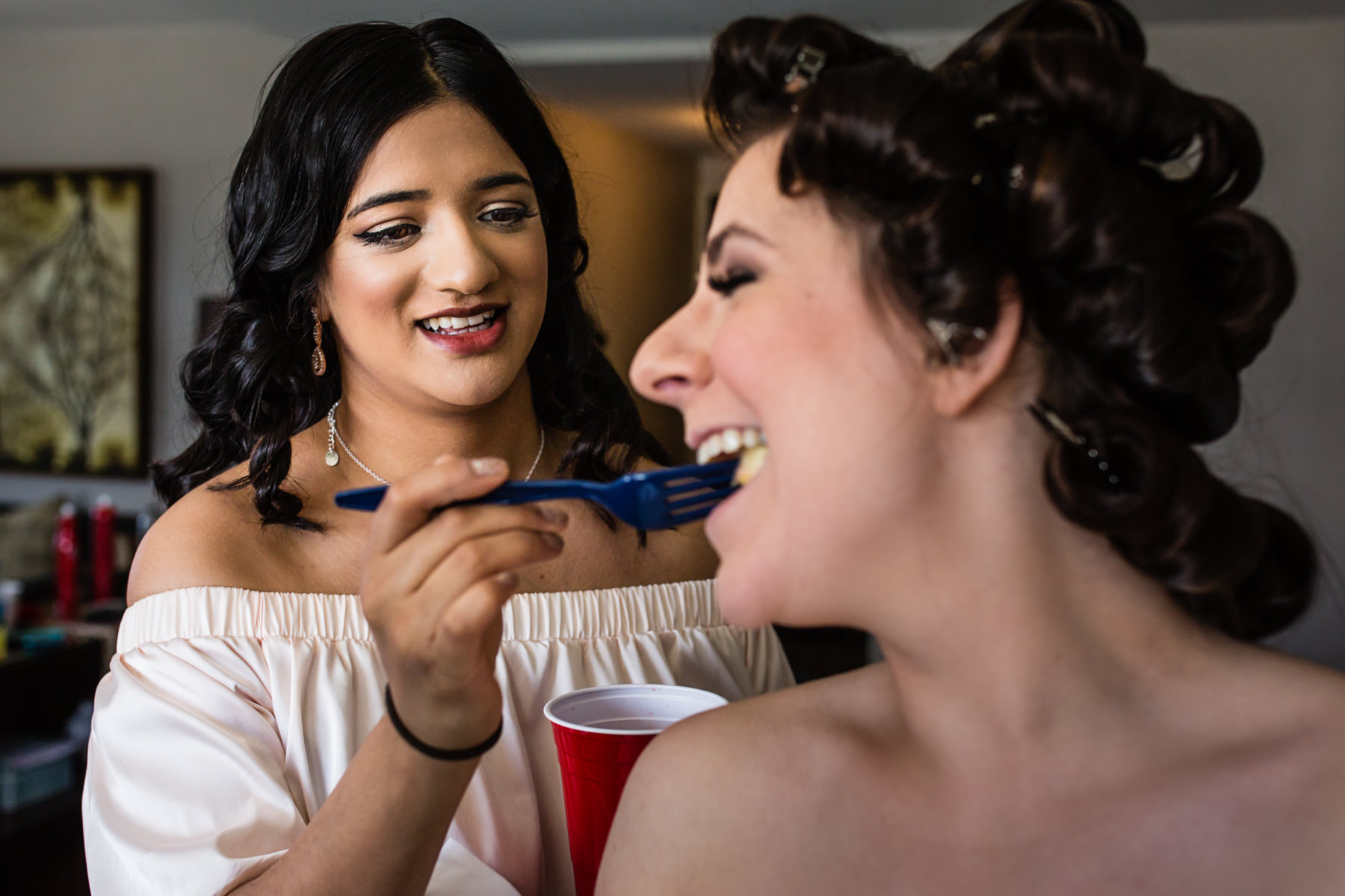 Helpful bridesmaid feeding the bride