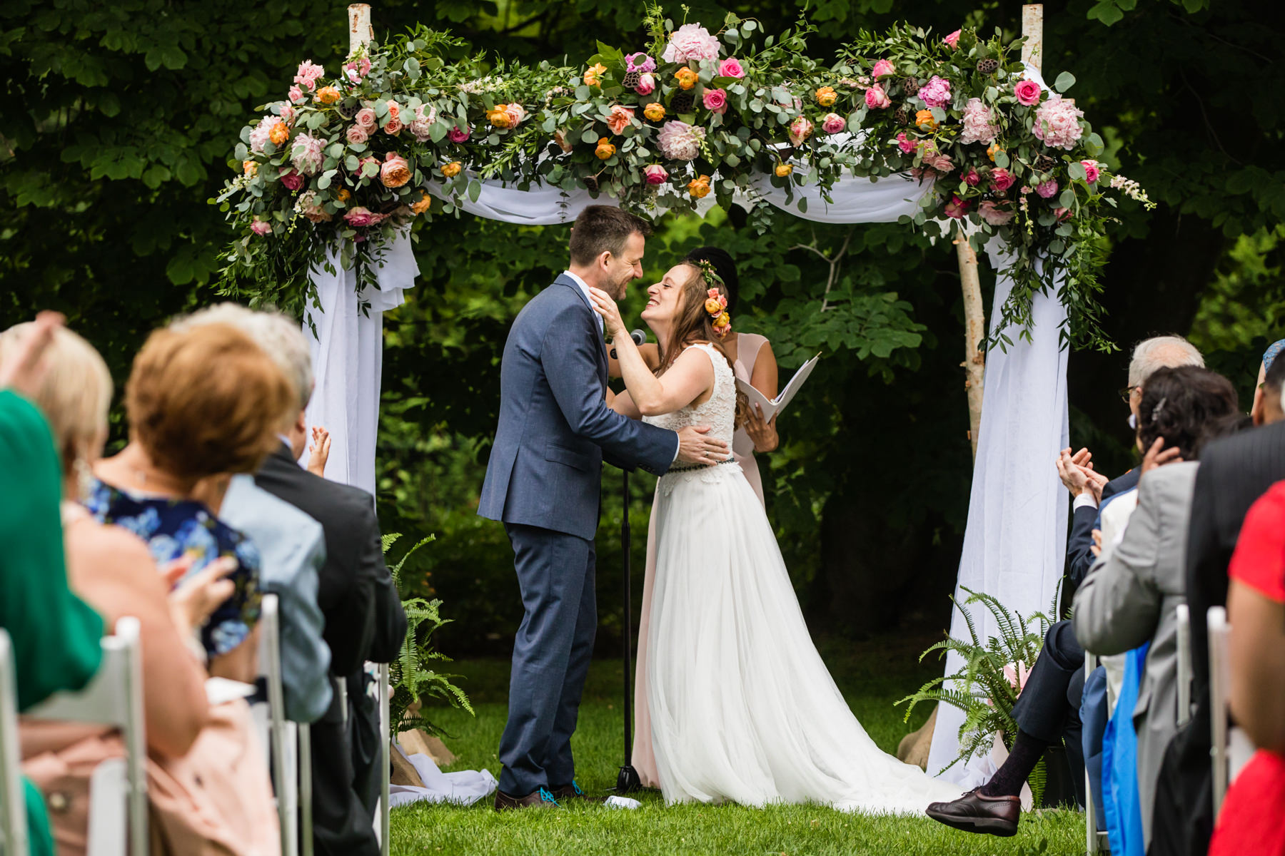 Bride and groom first kiss at outdoor wedding