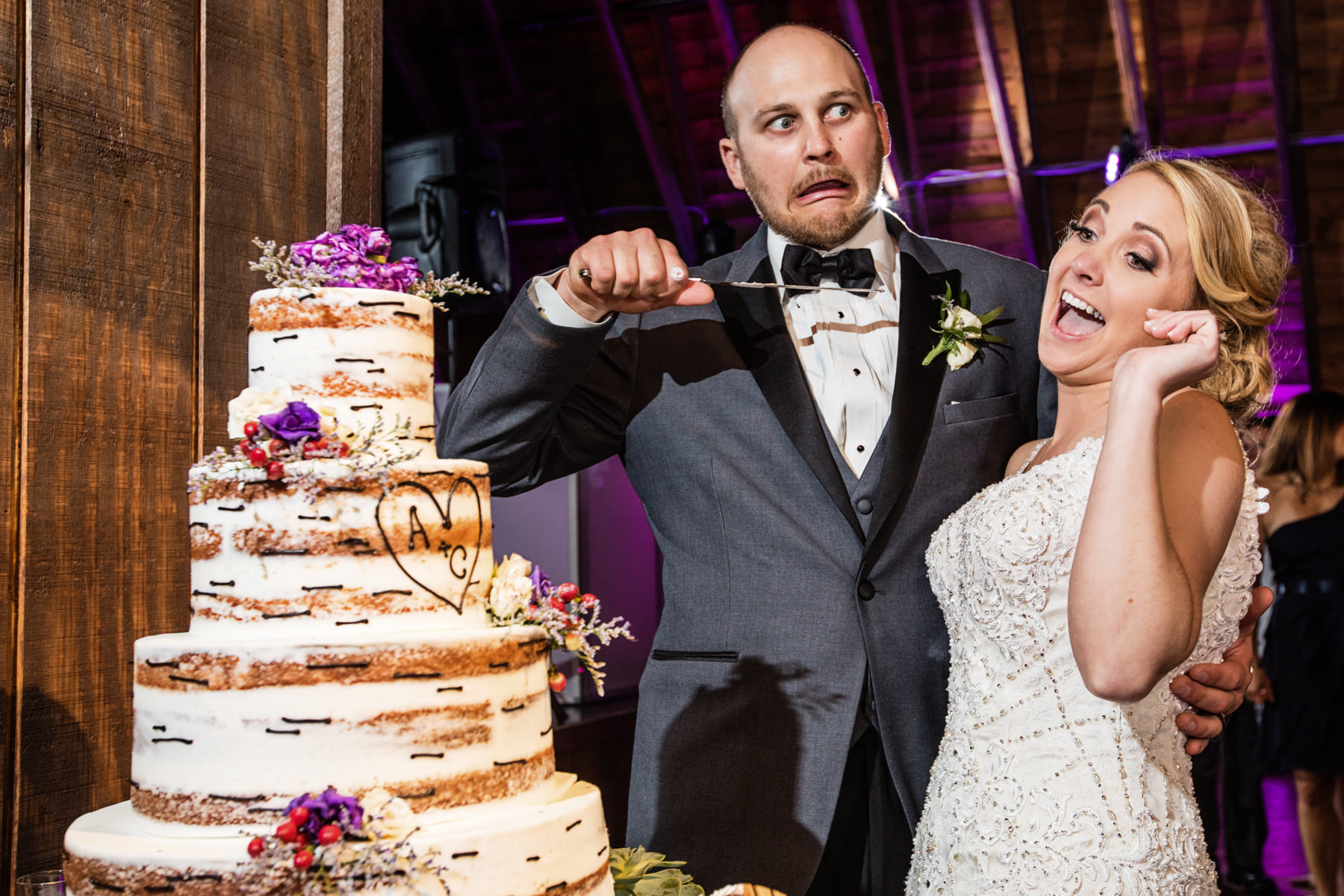 bride and groom playfully cut their wedding cake at Perona Farms reception