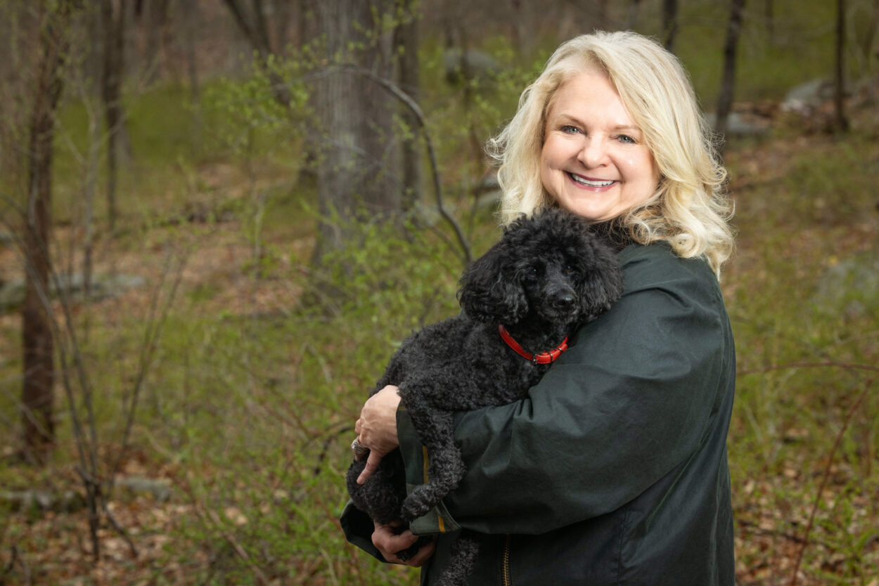 Beautiful older blond woman proudly holding her mini poodle during in-home pet photo session in Clinton NJ.