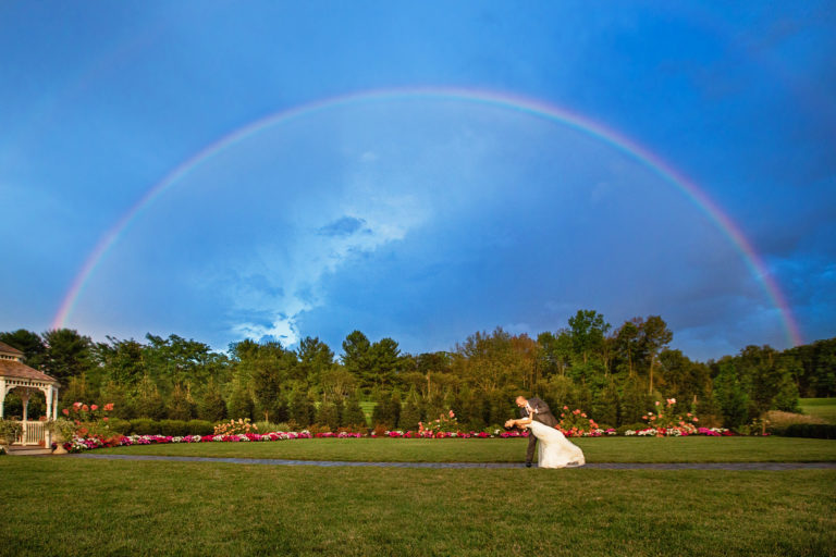 bride and groom dance under a rainbow