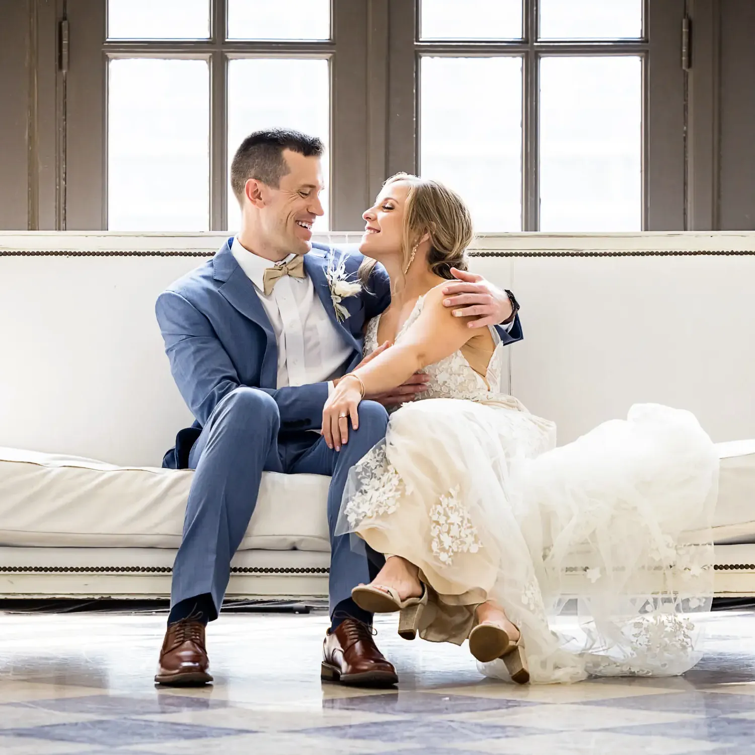 Wedding couple laughing on a couch together